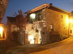 un antiguo edificio de piedra con balcón en una calle por la noche en Hotel Casona D'Alevia, en Alevia