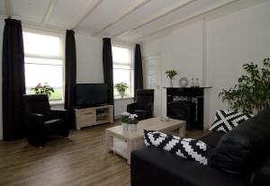 un soggiorno con divano e TV di Hof Van Lenthe appartementen a Dalfsen