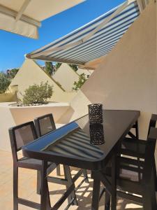 - une table et des chaises noires sur la terrasse dans l'établissement Studio Naturiste Design, au Cap d'Agde