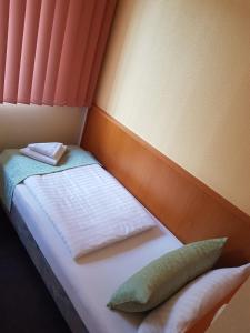 Hotel La Musica في Glessen: سرير صغير بملاءات بيضاء ومخدة