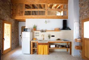 cocina con nevera blanca y armarios de madera en El Mas de Sant Vicenç - apartamentos rurales, en Arsèguel