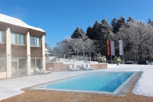 ein Schwimmbad im Schnee neben einem Haus in der Unterkunft Hotel Diehlberg in Olpe