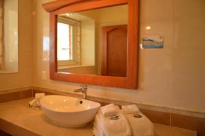 a bathroom with a sink and a mirror and towels at Hotel La Joya Isla Mujeres in Isla Mujeres