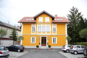een geel huis met auto's geparkeerd op een parkeerplaats bij Holiday Apartments by Das Grüne Hotel zur Post - 100 % BIO & Villa Ceconi in Salzburg