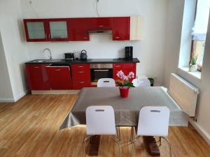 a kitchen with red cabinets and a table and chairs at Ferienwohnung Muldental in Grimma +7 photos