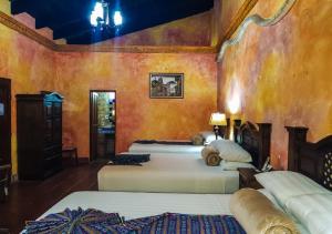 two beds in a room with orange walls at Hotel Eterna Primavera Antigua in Antigua Guatemala