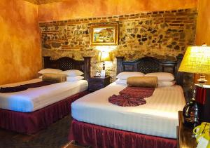 two beds in a room with a stone wall at Hotel Eterna Primavera Antigua in Antigua Guatemala