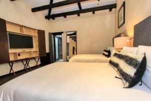 a bedroom with two beds and a tv at Uvence Arte + Hotel in San Cristóbal de Las Casas