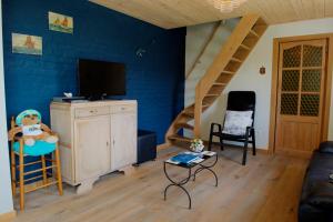Holiday Home Garnaalhuisje في أوستدوينكيرك: غرفة معيشة مع تلفزيون وجدار أزرق