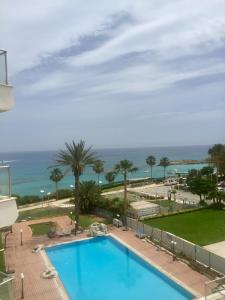 a swimming pool with the ocean in the background at PALLINIO COURT 402 Fig Tree Bay- Protaras Beach, IASONOS STR 7A in Protaras