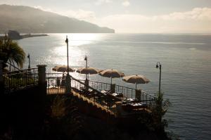 un gruppo di sedie con ombrelloni su un molo vicino all'acqua di The Cliff Bay - PortoBay a Funchal