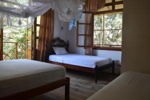 a bedroom with two beds and two windows at Hosteria Cabanas Itapoa in Puerto López