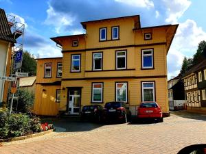 una casa amarilla con dos coches aparcados delante de ella en Zum krummen Hexenbuckel, en Bad Grund