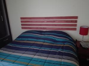 a bed with a striped comforter in a bedroom at Donde Lupe in Coihaique