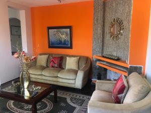 una sala de estar con 2 sofás y una pared de color naranja en Hostal Tutamanda 2 en Quito