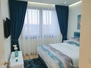 a bedroom with a large bed with blue curtains at Belgrade Waterfront-Delux apartman Beograd na vodi in Belgrade