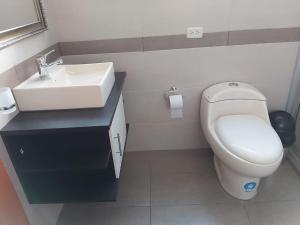 een badkamer met een wit toilet en een wastafel bij Hostal Tutamanda 2 in Quito