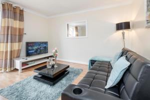 a living room with a couch and a tv at Thurrock, Grays -Spacious 3bd 3bath House Lakeside in Grays Thurrock