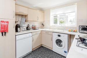 Una cocina blanca con lavadora y secadora. en Thurrock, Grays -Spacious 3bd 3bath House Lakeside, en Grays
