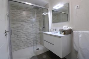 uma casa de banho branca com um chuveiro e um lavatório. em Casa Cervo Artes em Vila Nova de Cerveira