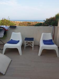 Duas cadeiras brancas com almofadas azuis numa varanda em Terrazza Anticaglie em Punta Braccetto