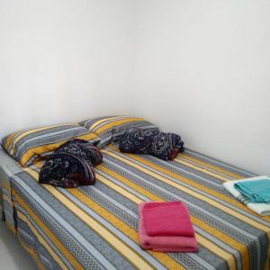a bed with colorful blankets and a pink pillow at Residencial Dom Laurindo in Paulo Afonso