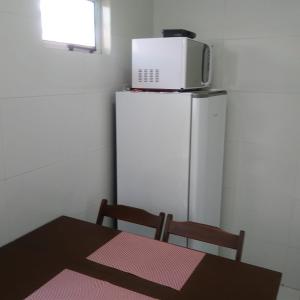 a table with a microwave on top of a refrigerator at Residencial Dom Laurindo in Paulo Afonso