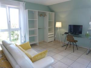 a living room with a white couch and a television at Les cerisiers in Bernardswiller
