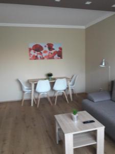 - un salon avec un canapé, une table et des chaises dans l'établissement Stúdió+19 Apartman, à Kazincbarcika