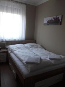 a bedroom with a large bed with a window at Stúdió+19 Apartman in Kazincbarcika