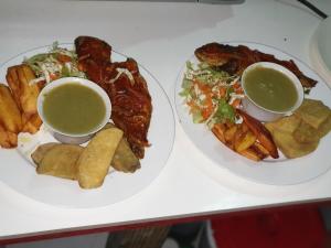 two plates of food with dipping sauce and french fries at Ti Kwen Glo Cho in Roseau