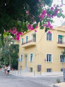 due persone che camminano davanti a un edificio giallo di Troon of Athens Apartments ad Atene