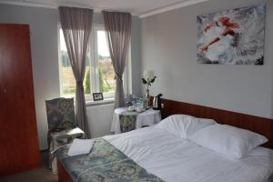 a bedroom with a bed and a chair and a window at Restauracja Hotel Kassandra in Września
