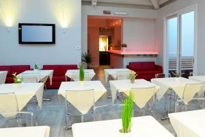 un ristorante con tavoli bianchi e divani rossi di Hotel Giotto a Torino