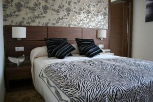 a bedroom with a bed with black and white sheets and pillows at Hotel Rural Neixon in Boiro