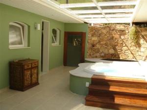 a large bathroom with a stone wall and a tub at Pousada Quinta dos Pássaros Itaipava in Itaipava