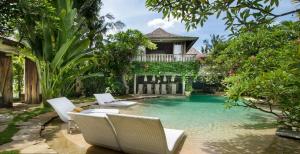 a swimming pool with chairs and a house at Phinisi Villas - Seminyak Beach in Seminyak