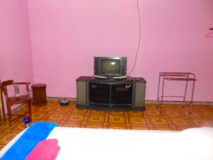 Zimmer mit einem TV, 2 Stühlen und einem Bett in der Unterkunft Aini Home Stay in Ternate