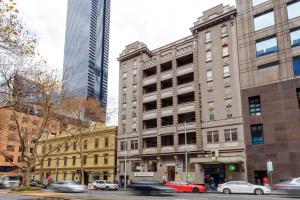 Un edificio in una strada di città con delle auto che lo attraversano di ibis Styles Kingsgate Hotel a Melbourne