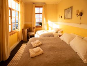 two beds in a hotel room with towels on them at Yendegaia House in Porvenir