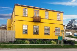 een geel huis met een balkon in een straat bij Yendegaia House in Porvenir