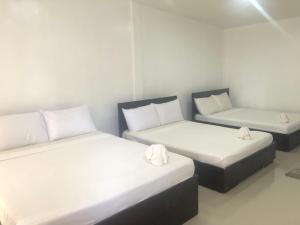 two beds in a room with white walls at Paguia’s Cottages in Mambajao