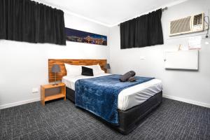 ein Schlafzimmer mit einem großen Bett mit einer blauen Decke in der Unterkunft Bald Hills Motel in Bald Hills