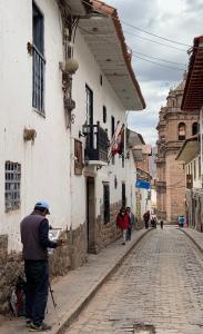 Un uomo in piedi sul lato di un edificio in una strada di Amerindia a Cuzco