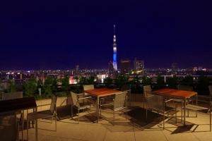 東京にあるTHE GATE HOTEL 雷門 by HULICのテーブルと椅子が備わり、夜は街のスカイラインを望めます。