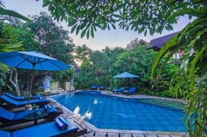 a swimming pool with blue chairs and umbrellas at Sri Phala Resort & Villa in Sanur