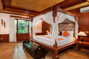 a bedroom with a canopy bed and a table at Sri Phala Resort & Villa in Sanur