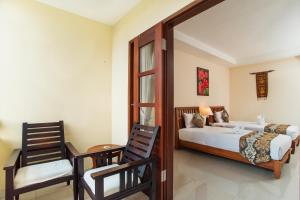 a bedroom with a bed and a chair and a mirror at Sri Phala Resort & Villa in Sanur