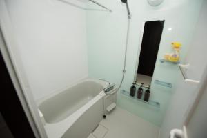 uma casa de banho branca com uma banheira e um espelho. em EX Itoman Apartment 401 em Itoman
