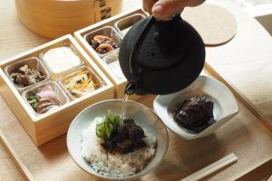 a person is pouring rice into a bowl of food at Hotel Koo Otsuhyakucho in Otsu